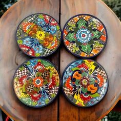 four colorful plates sitting on top of a wooden table