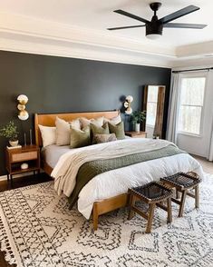 a bedroom with a large bed and two stools in front of the bed, along with a ceiling fan