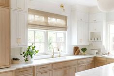 a kitchen filled with lots of white counter tops and wooden cabinetry next to a window