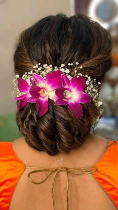 the back of a woman's head with flowers in her hair and an orange dress