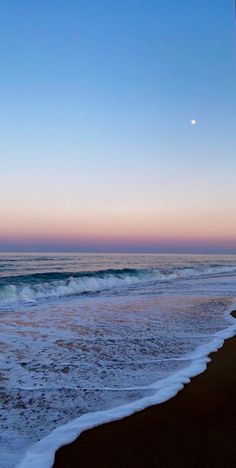 the beach is covered in white foam as the sun sets over the water and waves