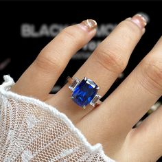 a woman's hand wearing a ring with a blue stone on it and diamond accents