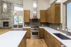 an empty kitchen with wood cabinets and white counter tops, stainless steel appliances and a fireplace