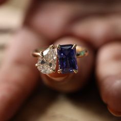 a person holding an engagement ring with two stones