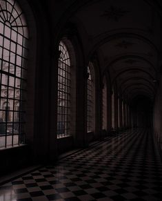 an empty hallway with large windows and black and white checkerboard flooring on both sides