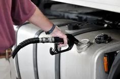 a man is pumping gas into his car's fuel tank with an electric pump