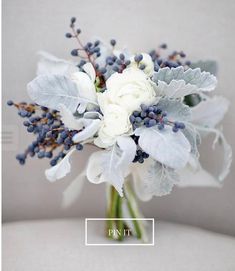 a bridal bouquet with white flowers and grey leaves on the back of a chair