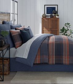 a bed in a bedroom with blue and orange plaid comforter set on top of it