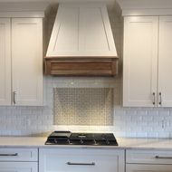 a kitchen with white cabinets and an oven hood over the stove, is shown in this image