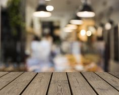 an empty wooden table top in front of a blurry image of a kitchen area