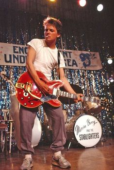 a man standing on stage with a red guitar