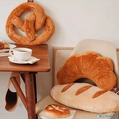 bread and coffee are sitting on the table next to each other in front of two large pretzels