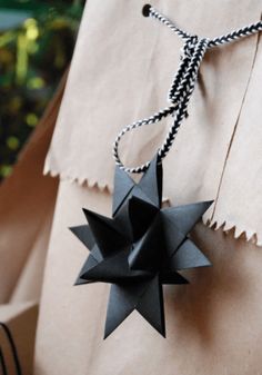 a black origami star hanging from a string on top of a brown paper bag