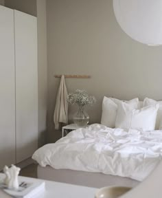 a bed with white sheets and pillows in a room