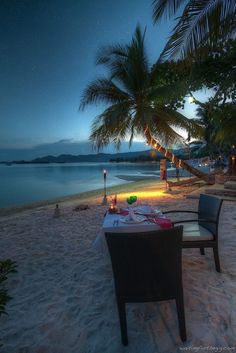 a table set up on the beach at night for two people to enjoy their meal