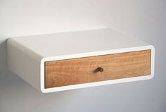 a white shelf with a wooden drawer on it