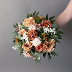 a bouquet of flowers is being held by someone's hand on a gray background