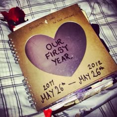 an open notebook with the words our first year written on it and a heart - shaped paper