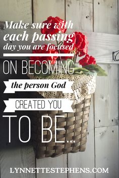 a basket filled with red flowers sitting on top of a wooden wall next to a sign that says, make sure each passing day you are focused on becoming the person god