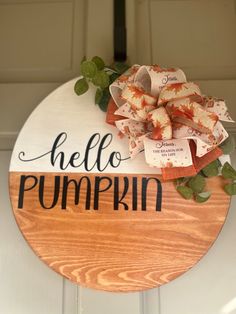 a wooden sign that says hello pumpkin hanging on the front door with leaves and ribbon