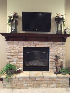 a living room with a stone fireplace and television mounted above the mantel, along with fake deer figurines