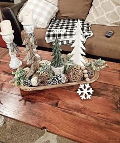 a wooden tray filled with christmas decorations on top of a table next to a couch