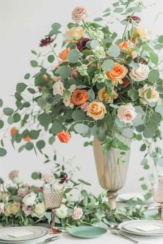 a vase filled with flowers on top of a table next to plates and silverware