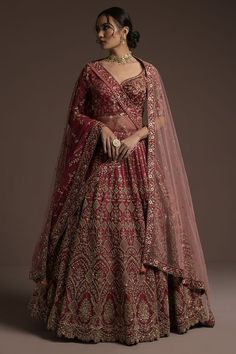 a woman in a red and gold lehenga, with her hand on her hip