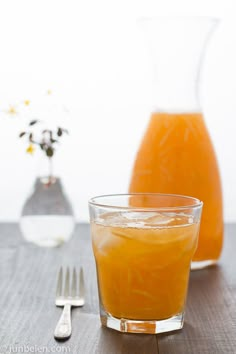 an orange juice in a glass next to a fork