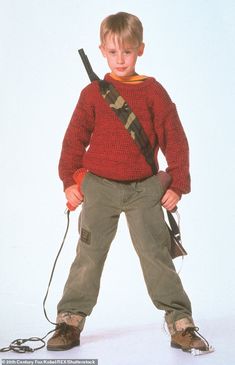 a young boy is holding a bag with a sling around his neck and standing in front of a white background