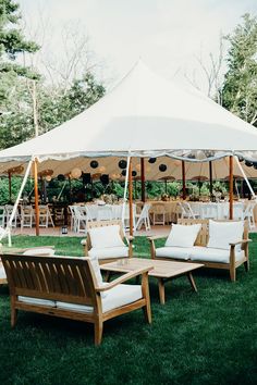 an outdoor seating area with tables and chairs under a tent