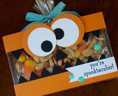 an orange box filled with halloween treats on top of a wooden table