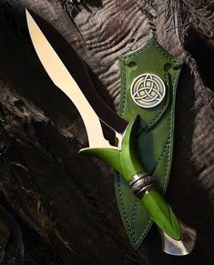 a knife and sheath sitting on top of a piece of green leather next to each other