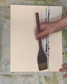 a person holding a brush over a piece of paper