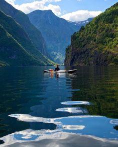 a person in a canoe on a lake surrounded by mountains