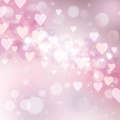 pink and white hearts are flying in the air on a blurry background with sparkles