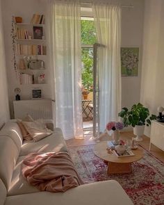 a living room filled with furniture and a large window covered in white drapes next to a wooden coffee table