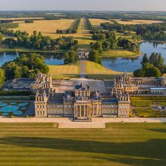 an aerial view of a large building in the middle of a field with water and trees