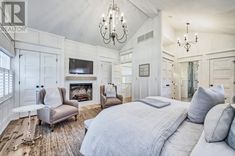 a large white bedroom with a fireplace and chandelier