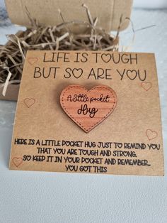 a wooden heart shaped brooch sitting on top of a piece of cardboard next to a box