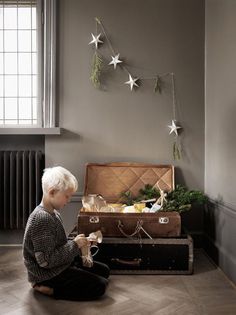 a young boy sitting on the floor next to an open suitcase