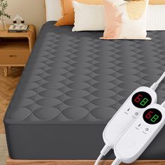 a bed with an alarm clock on it and two remote controls attached to the mattress