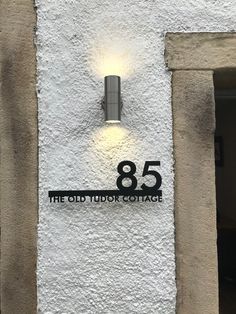 the old tudor cottage sign is lit up on the side of the building with a light