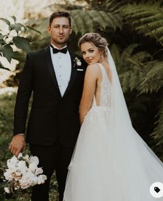 a bride and groom posing for a photo in front of greenery at their wedding