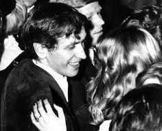 an old black and white photo of a man in a crowd smiling at someone else