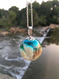 a close up of a glass ball on a chain with water in the back ground