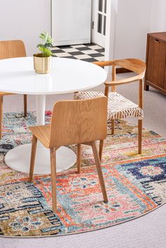 a white table with two chairs and a potted plant on it in a living room