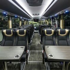 the inside of a bus with tables and chairs on it's sides, facing towards the rear