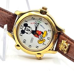 Featuring A Rare 1980's Lorus Disney Mickey Mouse Alarm Time Chime Animated Wristwatch V60f-6000 This Watch Is Untested And Will Need A Battery To Run. The Battery Retaining Clip Is Loose Inside The Watch Plastic Gold Toned Case That Has Portions Where The Gold Coating Is Worn Off. White 12-Hour Numeric Dial That Has A Mickey Mouse Graphic With 3 Expressions (Happy, Laughing & Surprise) That Can Be Changed By Turning The Dial And Appear To Coordinate With Alarm, Time & Chime And Animated Arms And White Gloved Hands. The Watch Does Appear To Play 1 Or 2 Disney Melodies. The Original Brown Leather Watch Band With Gold Tone Mickey Mouse Charm Is Included. Overall, The Condition Of Th Brown Leather Watch Band, Gloved Hands, Disney Gold, Brown Leather Watch, Leather Watch Band, Play 1, Disney Accessories, Leather Watch Bands, Disney Mickey Mouse