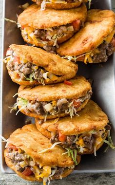 some tacos are stacked on top of each other in a metal tray and ready to be eaten